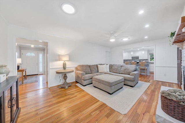 living room featuring ornamental molding, ceiling fan, light wood-type flooring, and recessed lighting