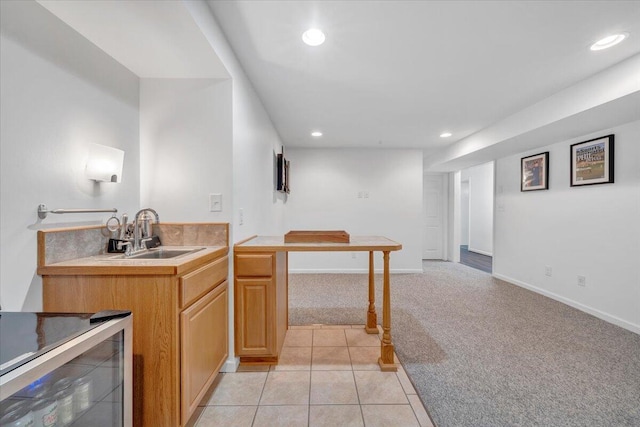 kitchen featuring a sink, light colored carpet, recessed lighting, wine cooler, and light countertops