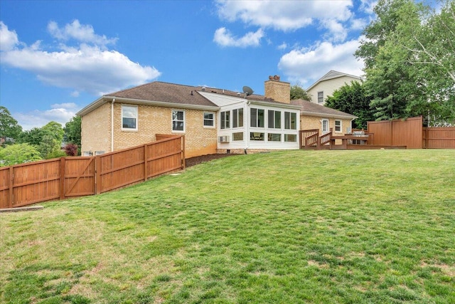 back of property featuring a sunroom, a chimney, brick siding, and a wooden deck