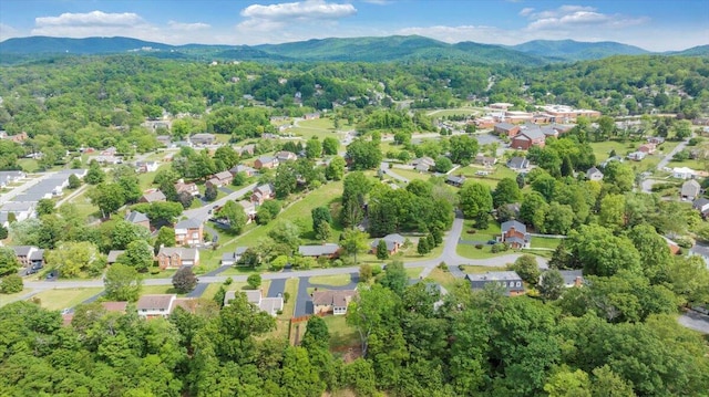 aerial view of property and surrounding area featuring a mountain backdrop, a forest, and nearby suburban area