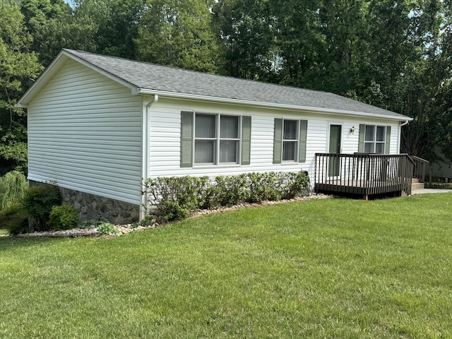 view of front of property with a front lawn, roof with shingles, and a deck