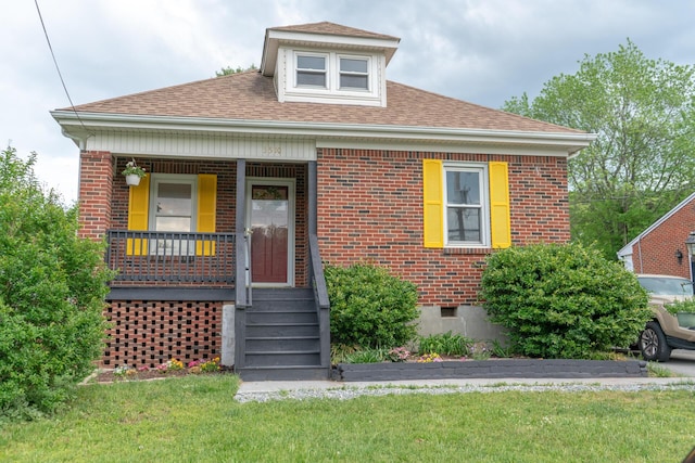 bungalow with covered porch, brick siding, a front lawn, and roof with shingles