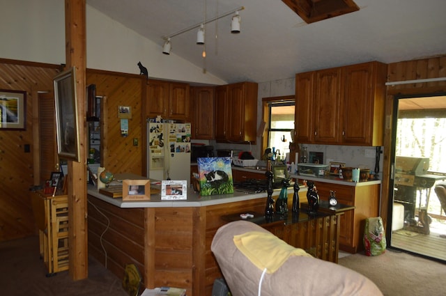 kitchen with white refrigerator with ice dispenser, lofted ceiling, wood walls, light countertops, and brown cabinets