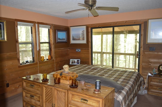 bedroom with access to outside, wooden walls, and a textured ceiling
