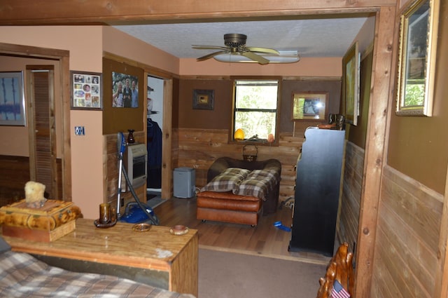 living room featuring a wainscoted wall, wood finished floors, ceiling fan, and a textured ceiling