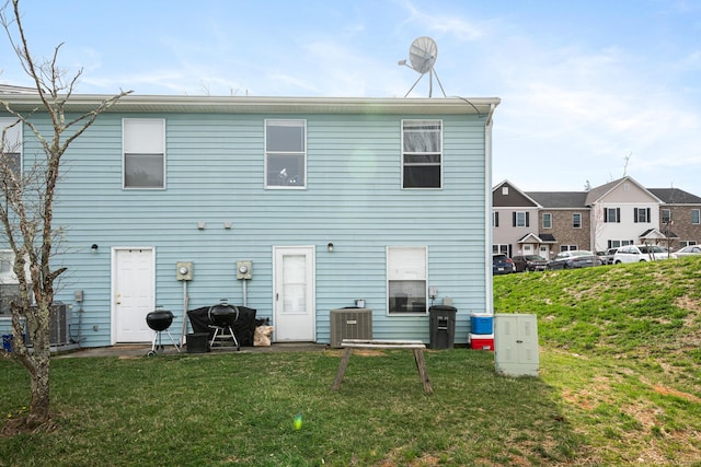 back of property featuring a lawn and central AC