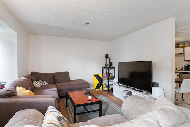 living room featuring a textured ceiling, visible vents, and wood finished floors