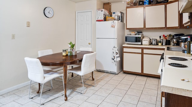 kitchen with freestanding refrigerator, under cabinet range hood, light countertops, and stainless steel microwave