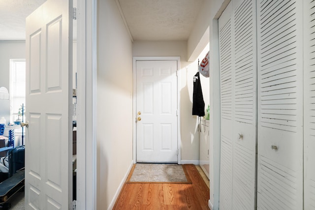 doorway featuring a textured ceiling, baseboards, and light wood-style floors