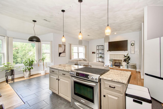 kitchen with electric range, freestanding refrigerator, baseboards, open floor plan, and hanging light fixtures