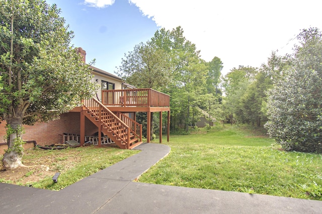 view of grassy yard featuring stairs and a deck