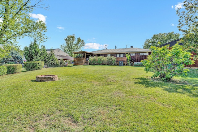 view of green lawn with stairway, a fire pit, and a deck
