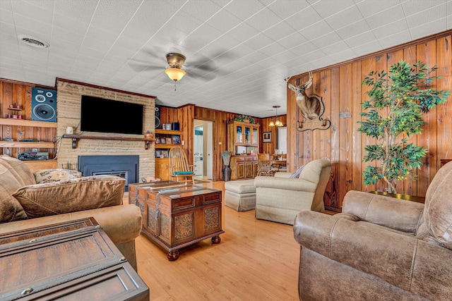 living room with wooden walls, a brick fireplace, and light wood finished floors