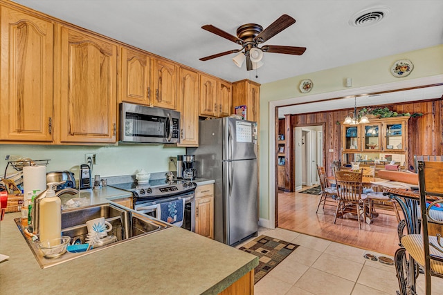 kitchen featuring appliances with stainless steel finishes, ceiling fan, light tile patterned floors, hanging light fixtures, and a chandelier