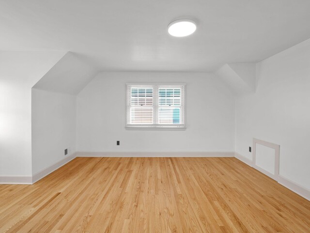 additional living space featuring wood finished floors, baseboards, and lofted ceiling