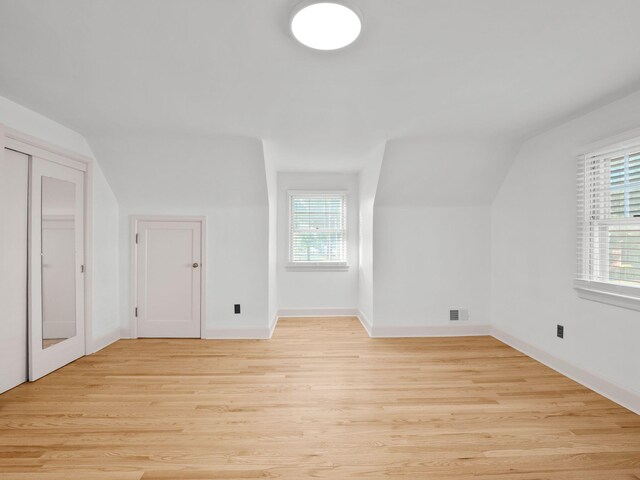 bonus room featuring light wood-type flooring, lofted ceiling, and baseboards