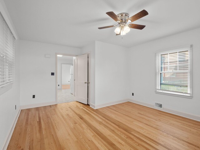 unfurnished room featuring light wood-type flooring, a ceiling fan, and baseboards