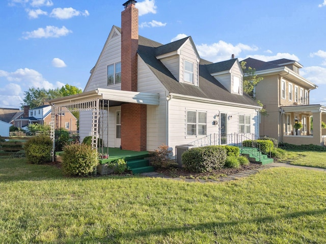 back of property with a chimney, a lawn, central AC unit, and roof with shingles