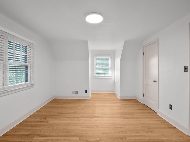 bonus room featuring light wood finished floors, vaulted ceiling, and baseboards