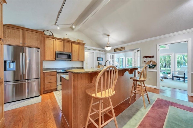 kitchen featuring appliances with stainless steel finishes, light wood-style flooring, a breakfast bar, brown cabinets, and hanging light fixtures