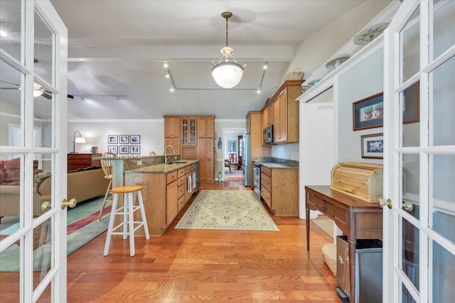 kitchen featuring a sink, brown cabinetry, french doors, light wood finished floors, and black microwave