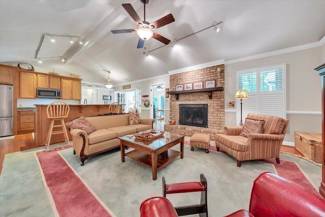 living room featuring rail lighting, ceiling fan, a fireplace, light wood finished floors, and crown molding