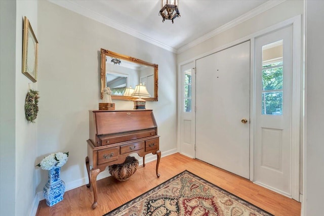 foyer entrance with light wood-style floors, ornamental molding, and baseboards