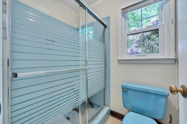 full bathroom with toilet, a stall shower, and baseboards