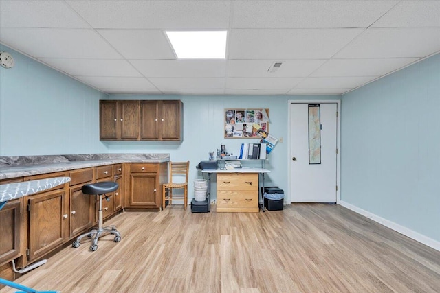 office space featuring light wood-style flooring, a drop ceiling, and baseboards