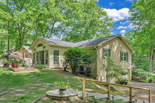 back of house featuring a garage, central AC unit, driveway, a wooden deck, and a yard