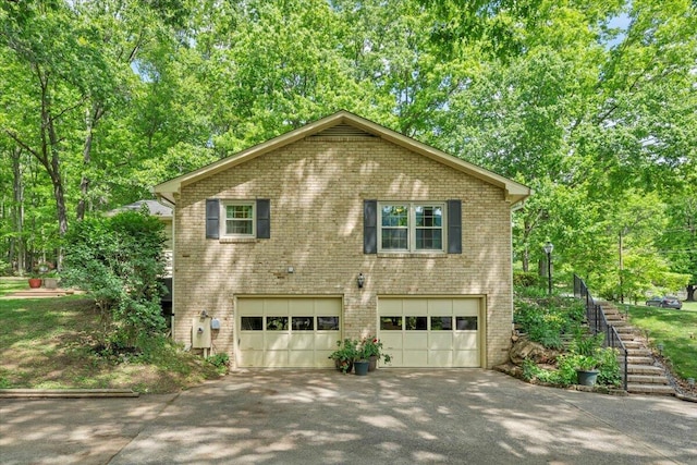 view of property exterior featuring driveway, an attached garage, brick siding, and stairs