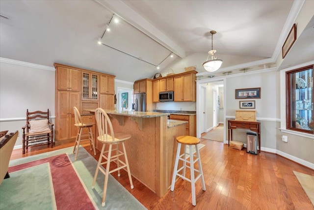 kitchen featuring appliances with stainless steel finishes, a breakfast bar area, lofted ceiling, light wood-type flooring, and glass insert cabinets