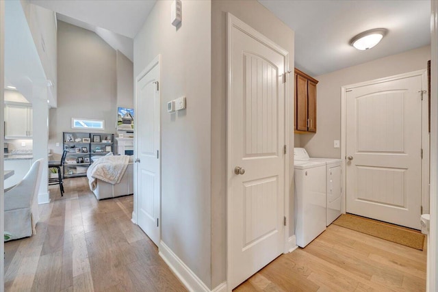 laundry area featuring cabinet space, separate washer and dryer, light wood finished floors, and baseboards
