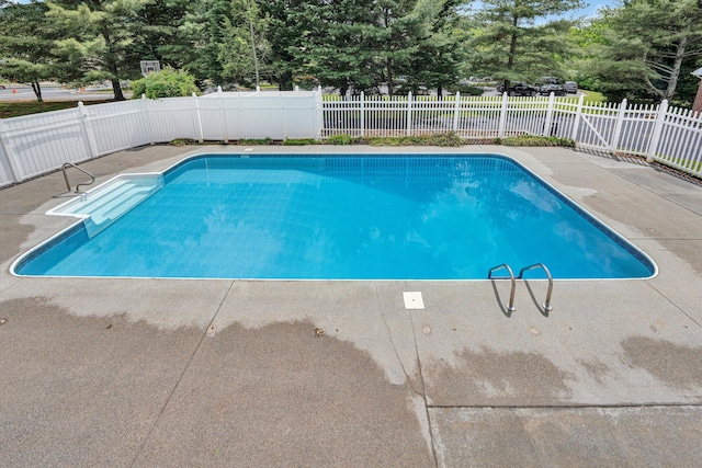 view of pool with a patio, a fenced backyard, and view of wooded area