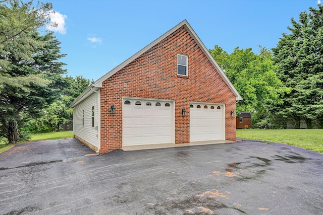 view of home's exterior featuring brick siding, a garage, an outbuilding, and a yard
