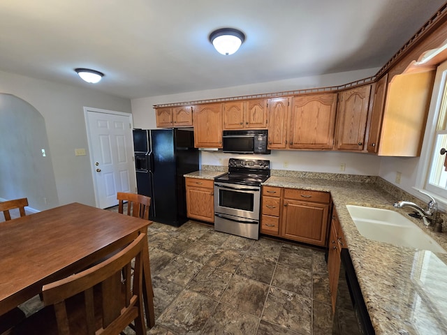 411 Raleigh Ave, Vinton, VA 24179 - kitchen featuring black appliances, a sink, arched walkways, light stone counters, and dark stone finish flooring