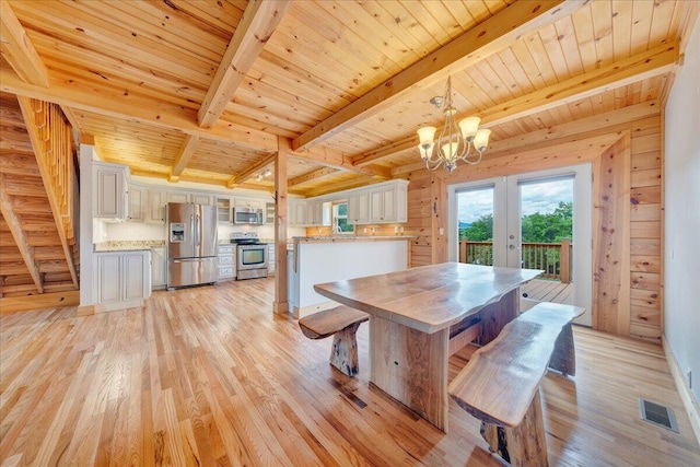 dining area featuring wooden ceiling, light wood-type flooring, beam ceiling, a chandelier, and french doors
