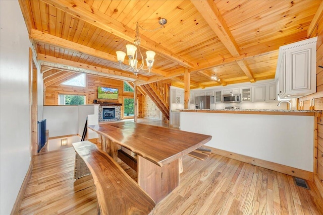 dining space featuring wood ceiling, light wood-type flooring, a chandelier, beamed ceiling, and baseboards