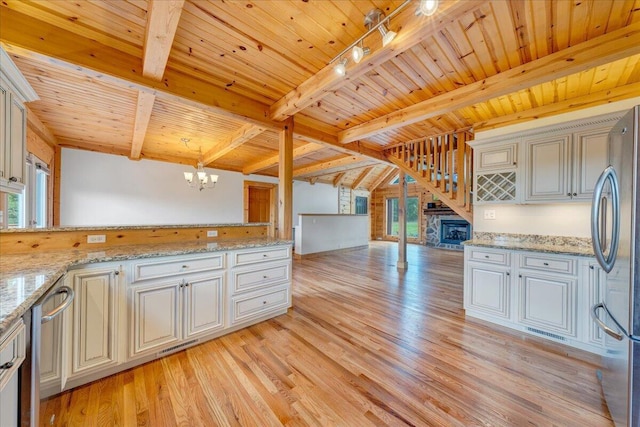 kitchen featuring a chandelier, appliances with stainless steel finishes, beamed ceiling, healthy amount of natural light, and wooden ceiling
