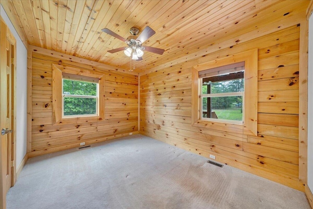 carpeted empty room featuring a ceiling fan, wood ceiling, and wood walls