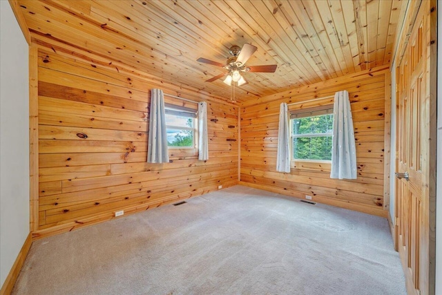 empty room featuring ceiling fan, carpet flooring, wooden walls, and wood ceiling