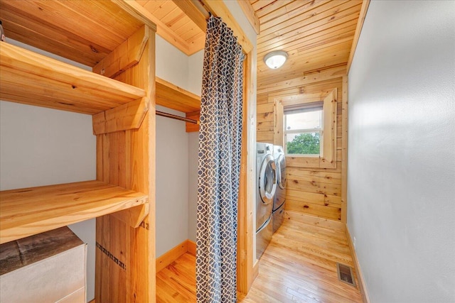 washroom with washer and clothes dryer, wood finished floors, wooden ceiling, wood walls, and baseboards