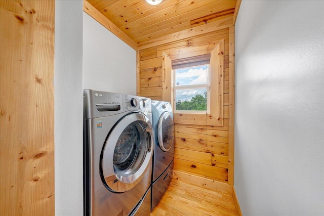 washroom featuring washer and clothes dryer, wood walls, light wood-style floors, baseboards, and wood ceiling