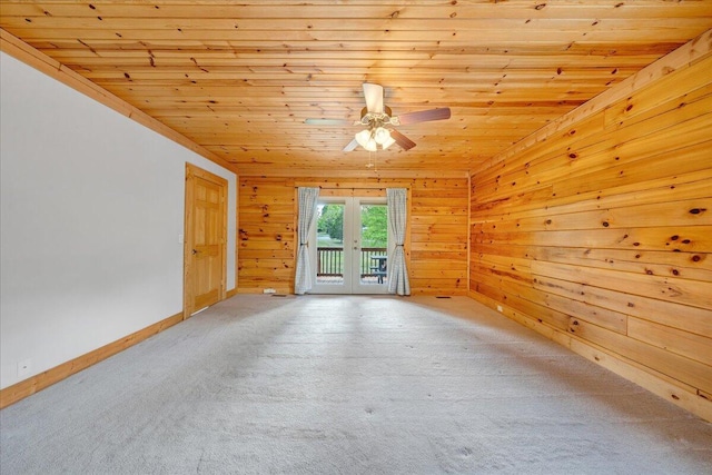 carpeted spare room featuring wooden ceiling, french doors, ceiling fan, wood walls, and baseboards