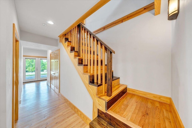 stairway with french doors, wood finished floors, and recessed lighting