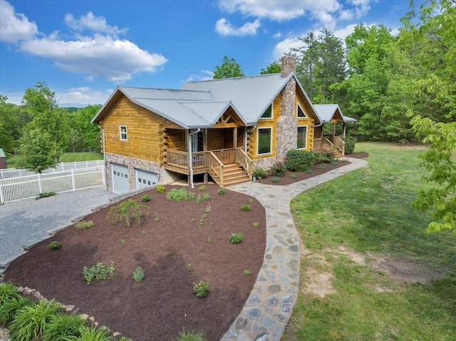 log-style house featuring a porch, gravel driveway, a chimney, a garage, and stone siding