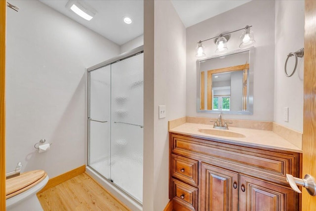 full bathroom with a stall shower, wood finished floors, toilet, and vanity