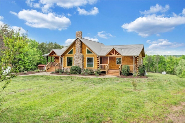 log-style house featuring covered porch, a chimney, a front lawn, metal roof, and stone siding