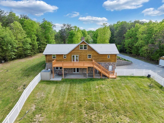 rear view of house with stone siding, stairs, a deck, and a view of trees