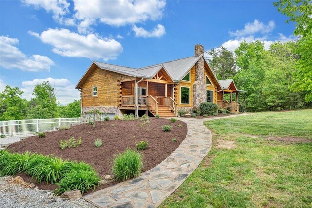 log cabin with a chimney, covered porch, log exterior, metal roof, and stone siding